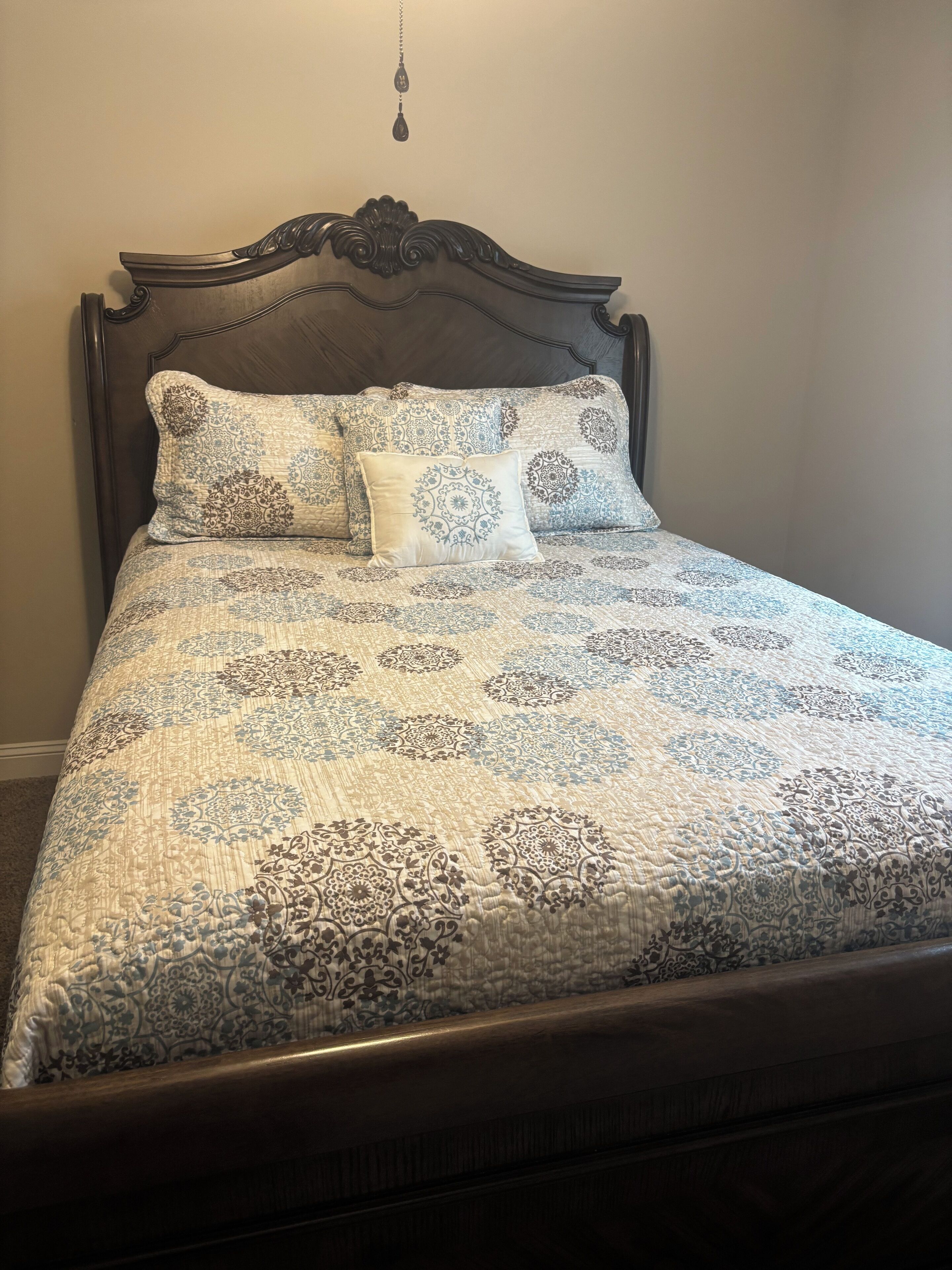 A bed with a dark wooden headboard and a patterned bedspread.