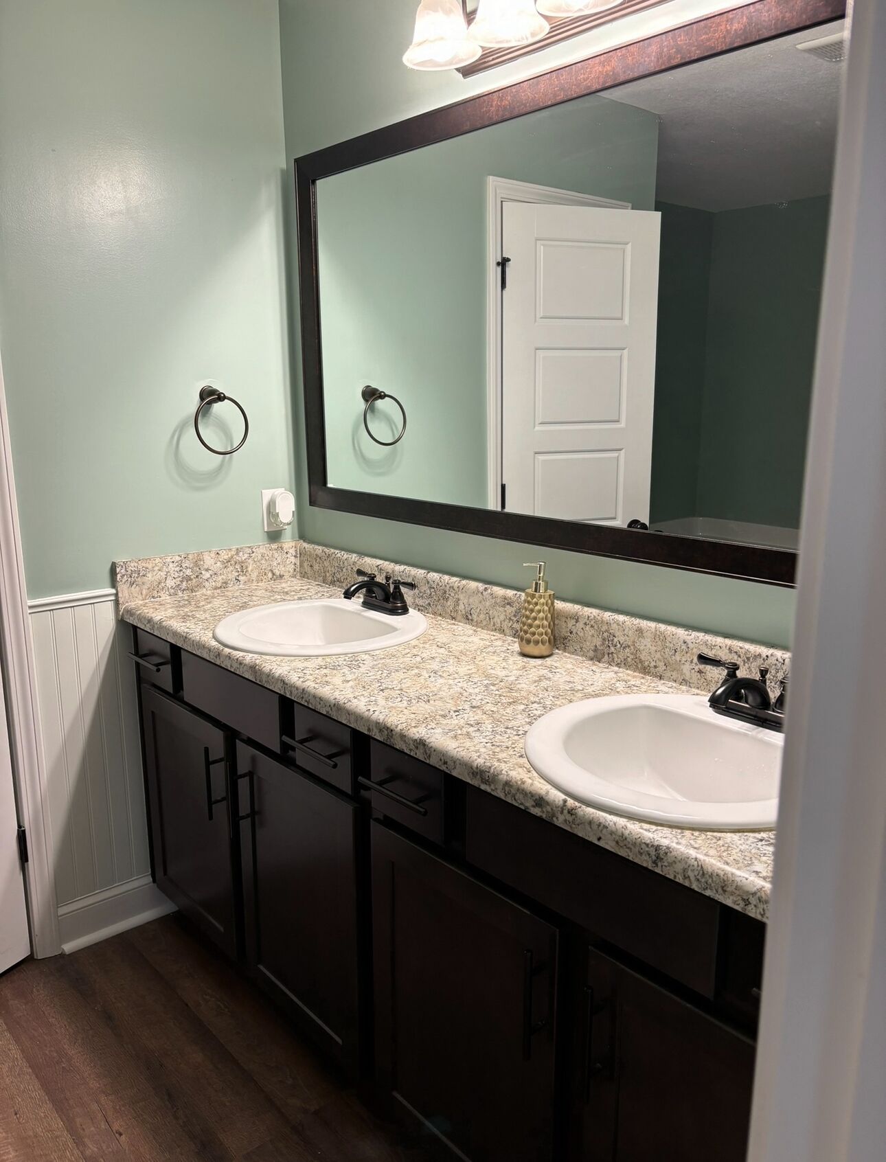 A bathroom with two sinks, a large mirror, and a door.