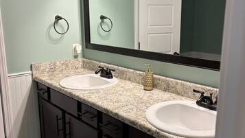 A bathroom with two sinks, a large mirror, and a door.