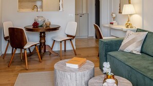 A modern living room with a green sofa, round coffee tables, and a dining area with chairs and a table. - Parisian-Inspired 1BR in the Heart of Bucharest - Balcony, AC & Fully Equipped (Bucharest)
