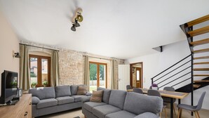 A modern living room with a grey sectional sofa, a wooden coffee table, and a dining area with a wooden table and chairs.