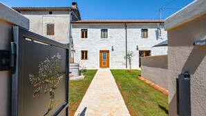 A courtyard with a stone pathway leading to a building with a wooden door.