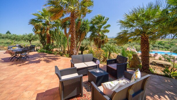 An outdoor patio with wicker furniture, a dining table, and chairs.
