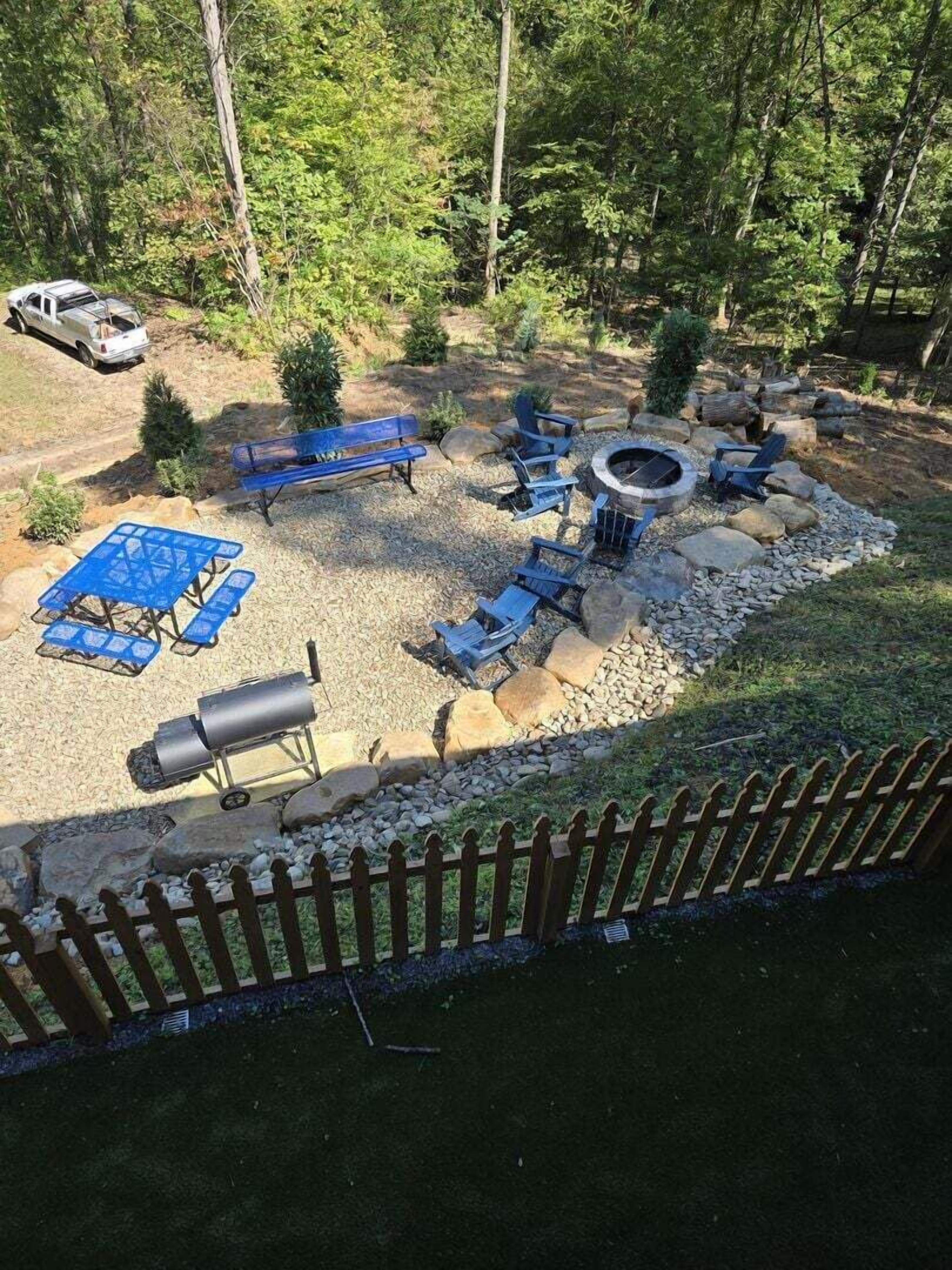A backyard with a barbecue area, blue patio furniture, and a wooden fence.