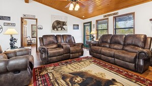 A cabin interior with leather sofas, a large rug with a bear design, wooden ceiling, and a ceiling fan. - Secluded Cubs Den Retreat in Wears Valley – Sleeps 10, Hot Tub, Pool Table, Dog-Friendly (Sevierville)