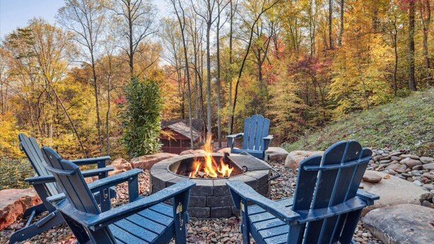A fire pit surrounded by Adirondack chairs in a forested area. - Secluded Cubs Den Retreat in Wears Valley – Sleeps 10, Hot Tub, Pool Table, Dog-Friendly (Sevierville)
