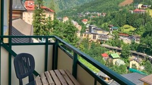 A balcony with a view of a mountainous landscape, a wooden table, and a plastic chair. - Mountain-view Apartment in Salzburg (Bad Gastein)