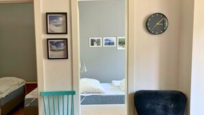 A room with a bed, a chair, a clock, and framed pictures on the wall. - Mountain-view Apartment in Salzburg (Bad Gastein)