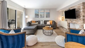 Un salon moderne avec un canapé d’angle, une table basse ronde et une cheminée.