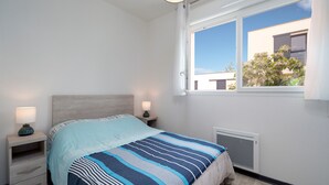 A bedroom with a bed, bedside tables, a window, and a radiator. - Sweet home duplex 6 pers (Sérignan)