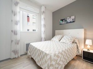 Relax in this serene bedroom with a large bed, bedside table, and wall-mounted artwork.