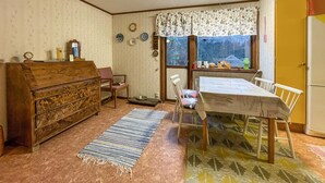 A cozy kitchen with a wooden table, chairs, a refrigerator, and a window with a floral curtain. - 1 bedroom gorgeous home in Svenljunga (Svenljunga)