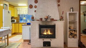 A living room with a fireplace, yellow cabinets, a microwave, and a dining area. - 1 bedroom gorgeous home in Svenljunga (Svenljunga)