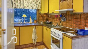 A kitchen with yellow cabinets, a stove, and a window with a view of trees. - 1 bedroom gorgeous home in Svenljunga (Svenljunga)