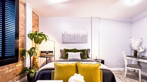 Un dormitorio moderno con cama, mesita de noche, lámpara y escritorio con silla.