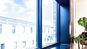 Una ventana con vista a un edificio de varias ventanas y pared de ladrillo.