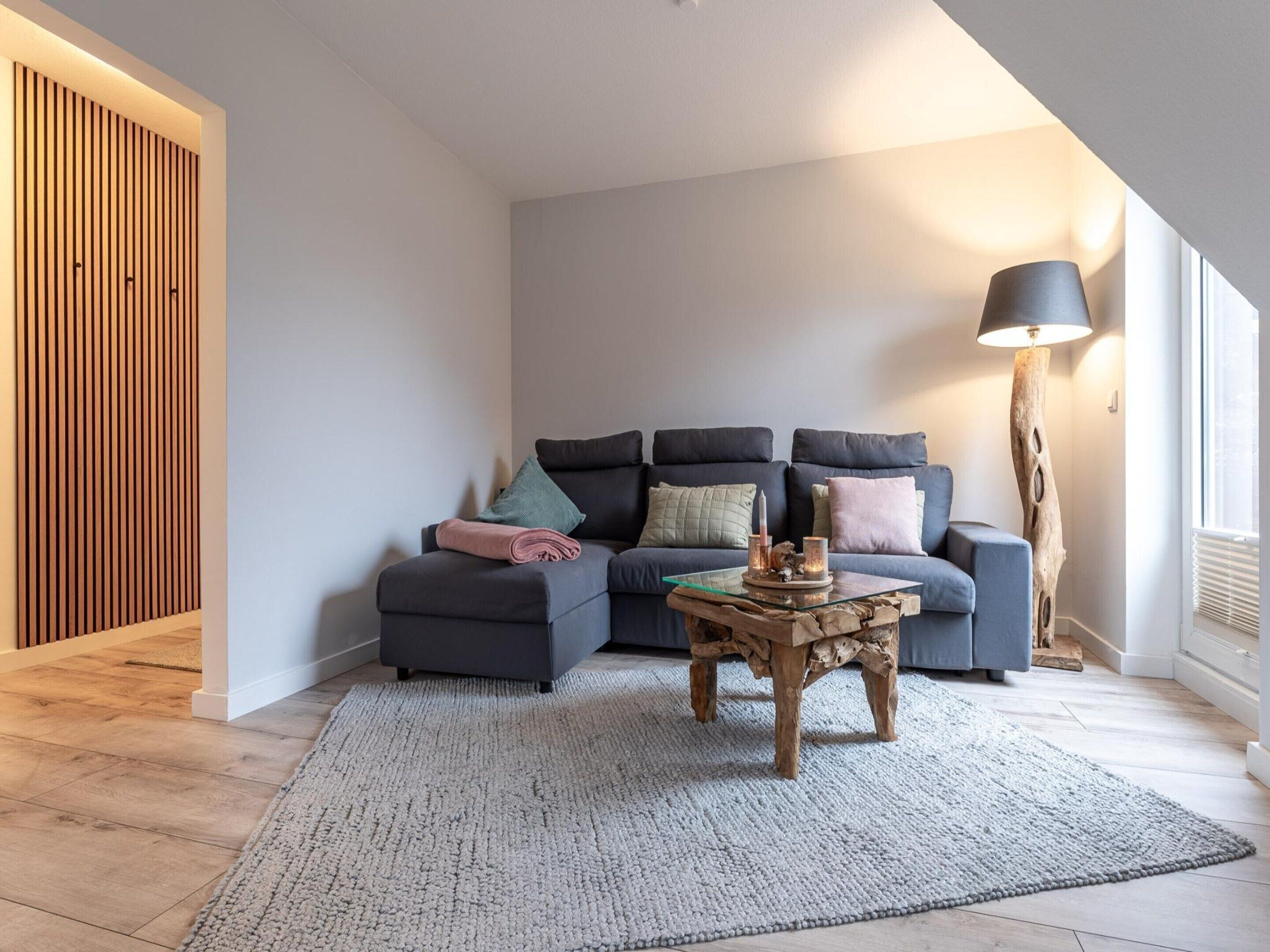 Una sala de estar moderna con un sofá modular, una mesa de centro de vidrio y una lámpara de pie.