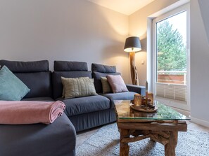 A modern living room with a dark-colored sofa, a glass coffee table, and a lamp.