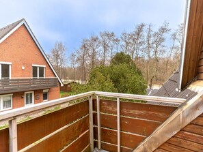 A residential area with a brick house, a wooden deck, and a view of trees and a green bush.