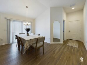 A dining area with a wooden table and chairs, a chandelier, and a view of a door and hallway. - Perfectly Placed in Moultrie Creek (Sumter County)