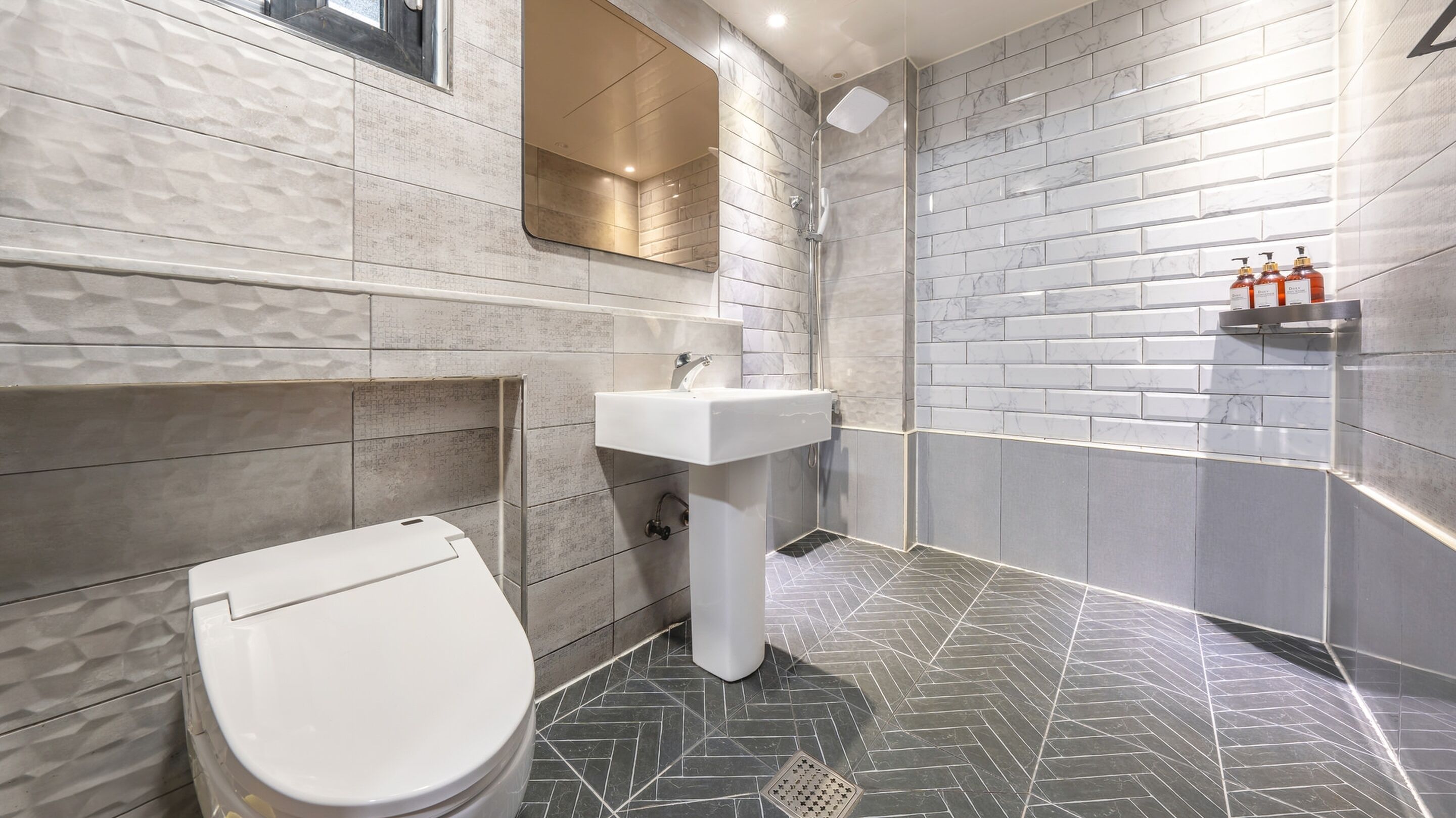 A modern bathroom with a white toilet, a pedestal sink, and a shower.