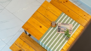 Een houten tafel met een geruite tafelkleed, een krant en een glazen vaas met een plant.