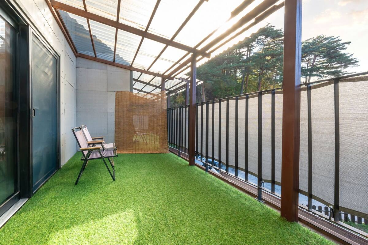 A balcony with artificial grass, a chair, and a wooden structure.