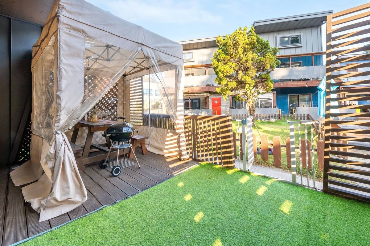A patio with a grill, a tent, and a small garden area.