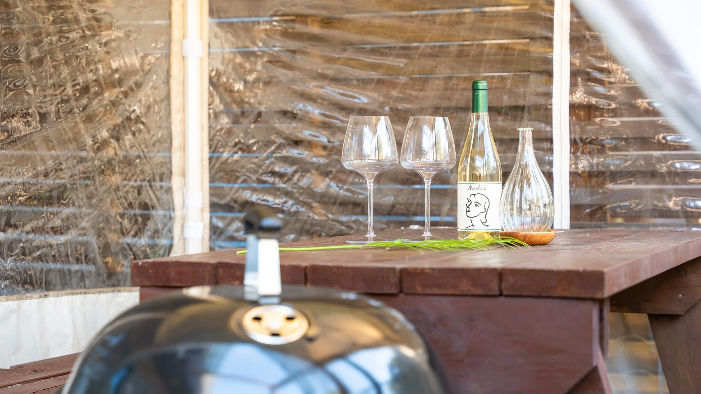 Una mesa de madera con copas de vino, una botella de vino y una botella de agua.