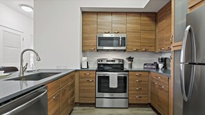 A modern kitchen with stainless steel appliances, wooden cabinets, and a built-in microwave.