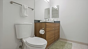Et badeværelse med toilet, et træskab, et spejl og en håndklædestang.