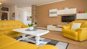 A modern living room with yellow sofas, a white coffee table, and a TV mounted on the wall. - Beautiful Apartment in Prime Location (Porec)