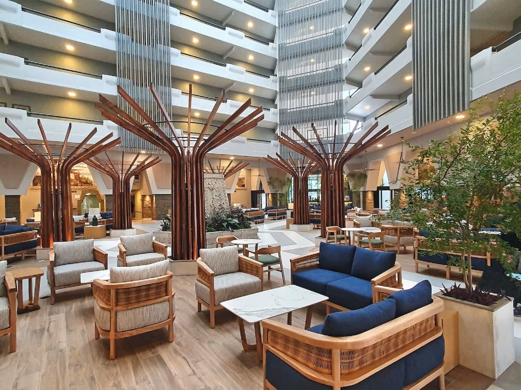 A spacious lobby with high ceilings, wooden tree-like structures, and comfortable seating areas.