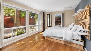 Ein Schlafzimmer mit einem großen Fenster, einem Bett und einem Holzkopfstück.