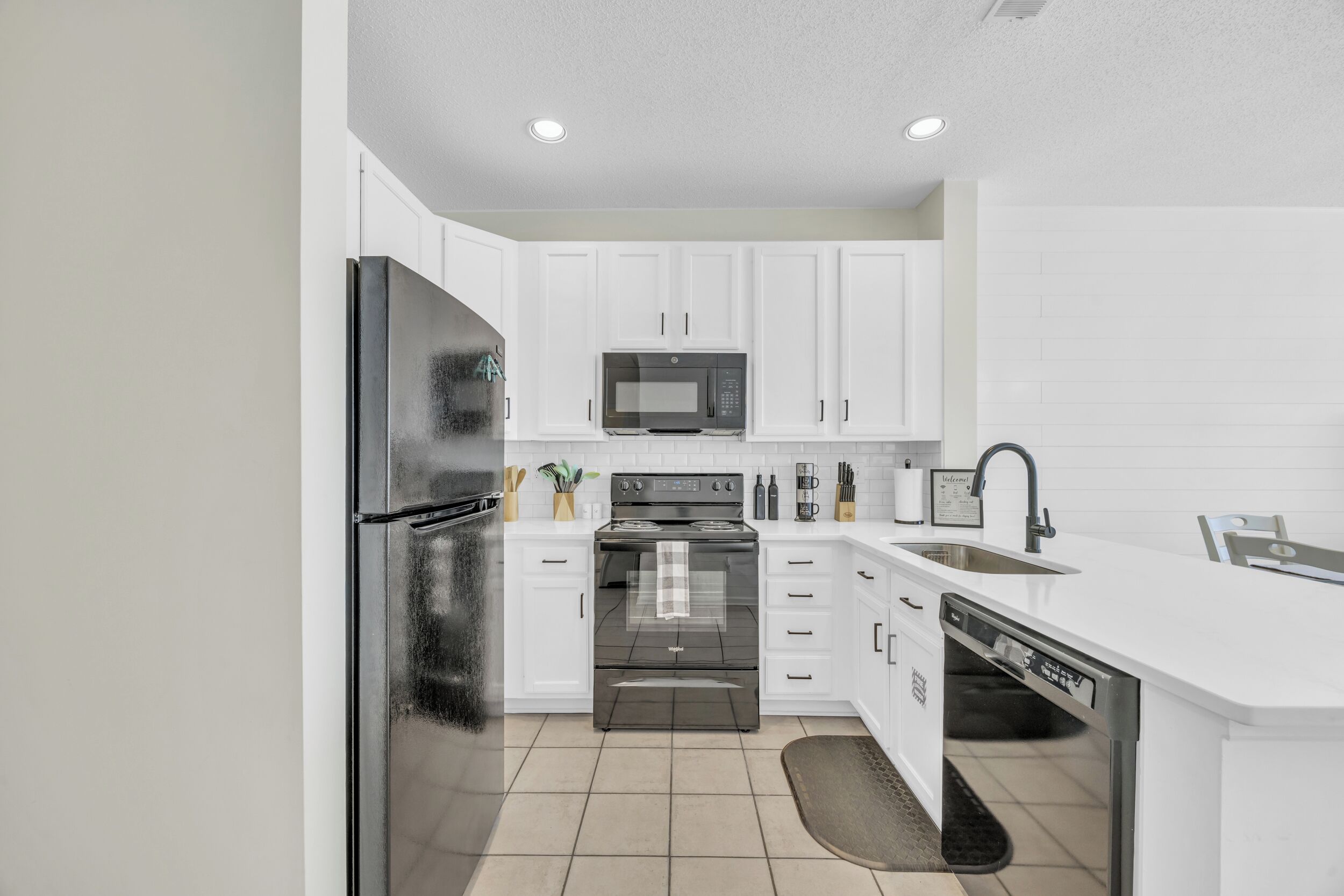 A modern kitchen with white cabinets, stainless steel appliances, and a built-in dishwasher.