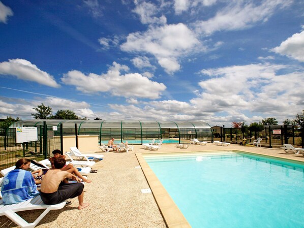 A swimming pool area with lounge chairs and a covered seating area.
