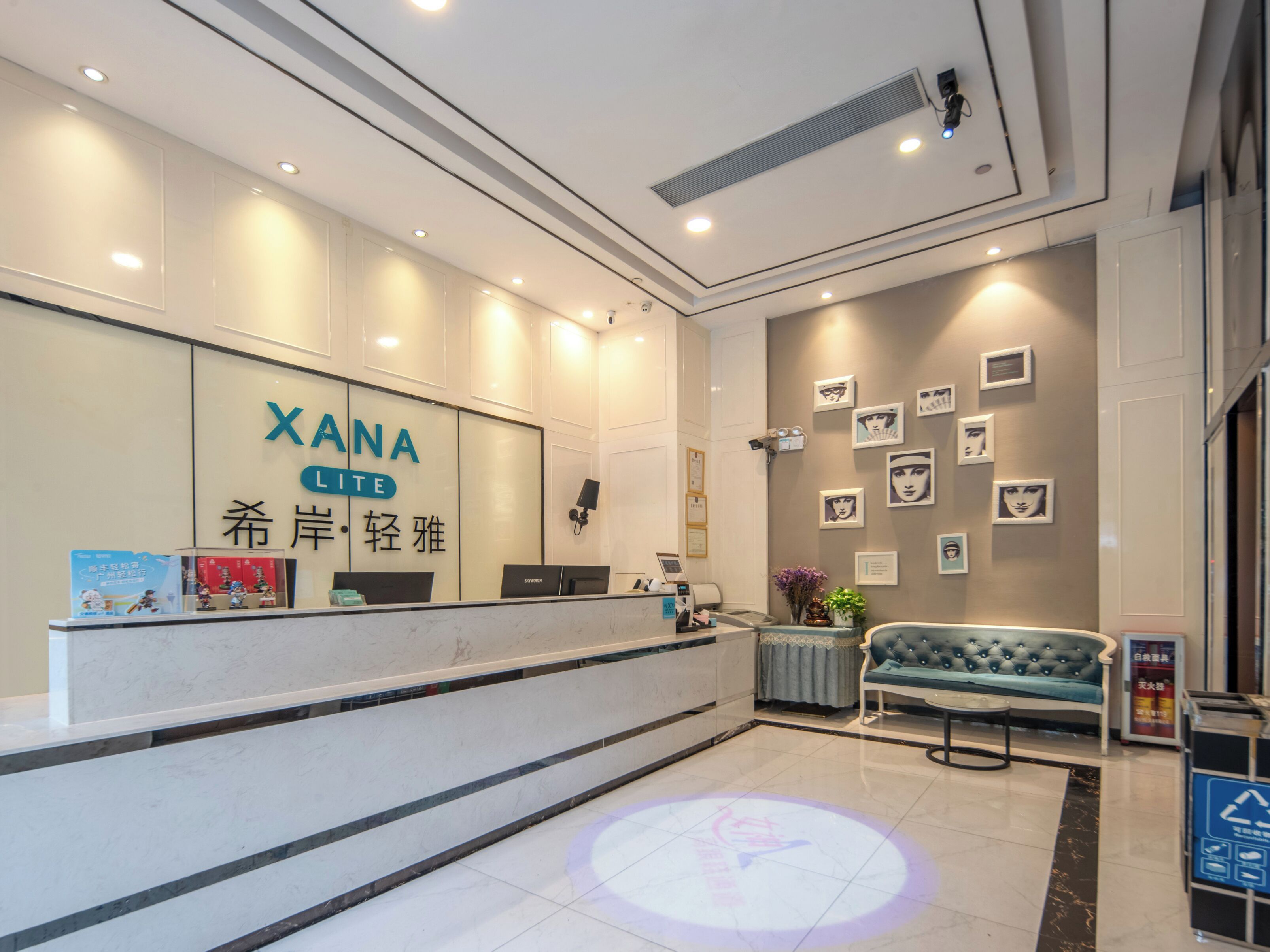 A reception area with a counter, a sofa, and framed pictures on the wall.