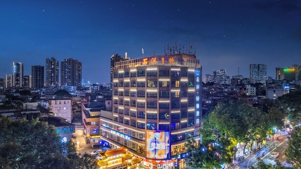 Ein mehrstöckiges Hotel mit modernem Design, das durch eine große, beleuchtete Schilderung und zahlreiche Balkone gekennzeichnet ist.