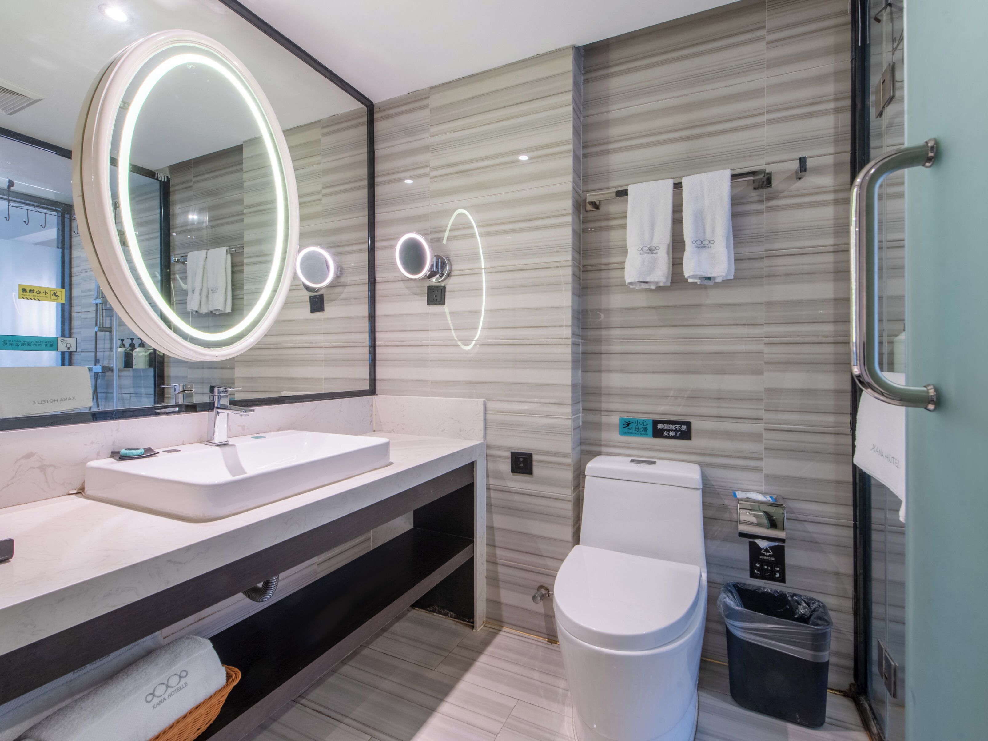 Un baño moderno con un espejo grande, un inodoro y un lavamanos.