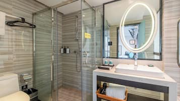 A modern bathroom with a glass-enclosed shower, a large mirror with a light, and a white sink.