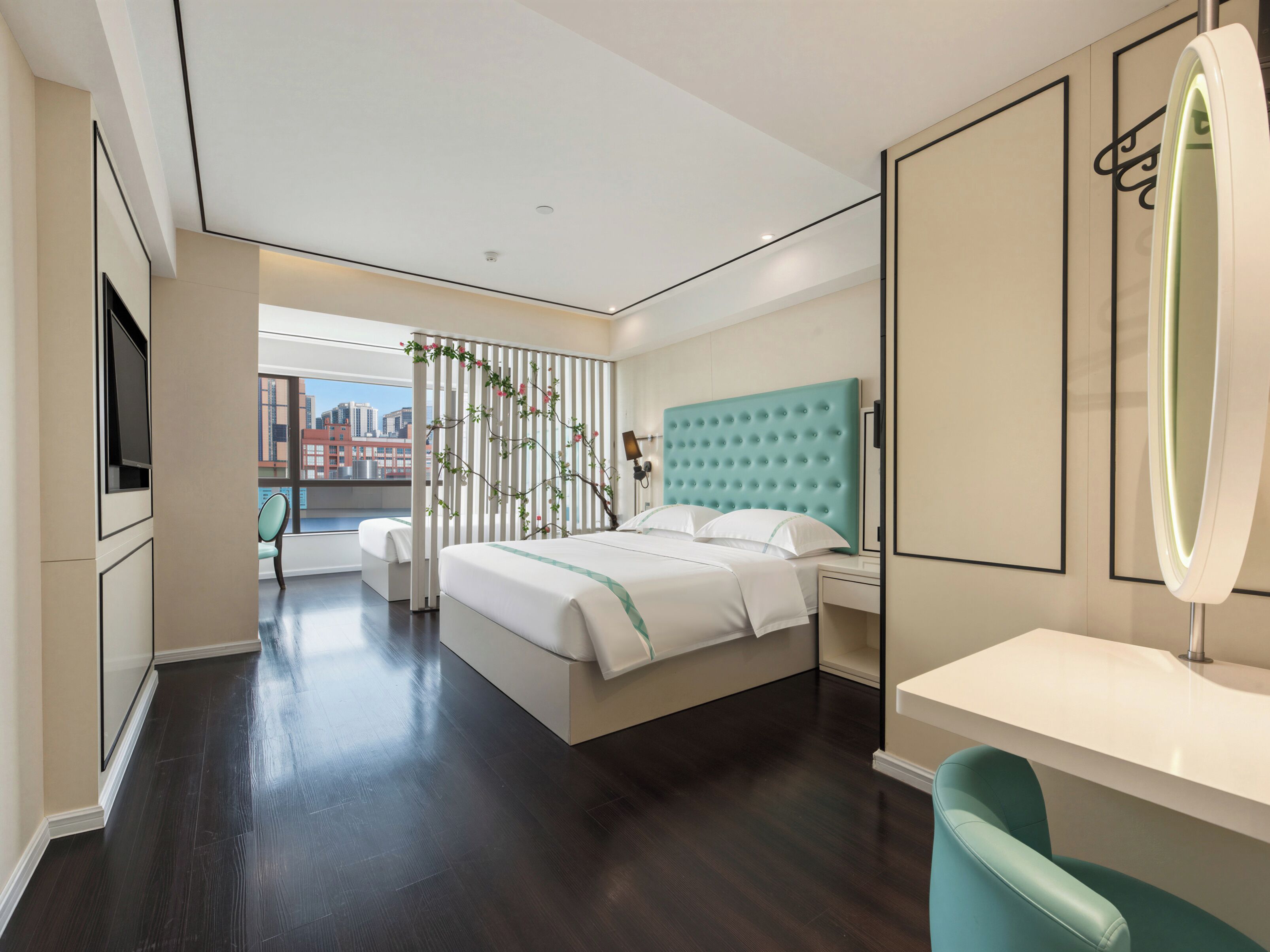 Een moderne hotelkamer met een groot bed, een zithoek, een badkamer met spiegel en uitzicht op de stad.