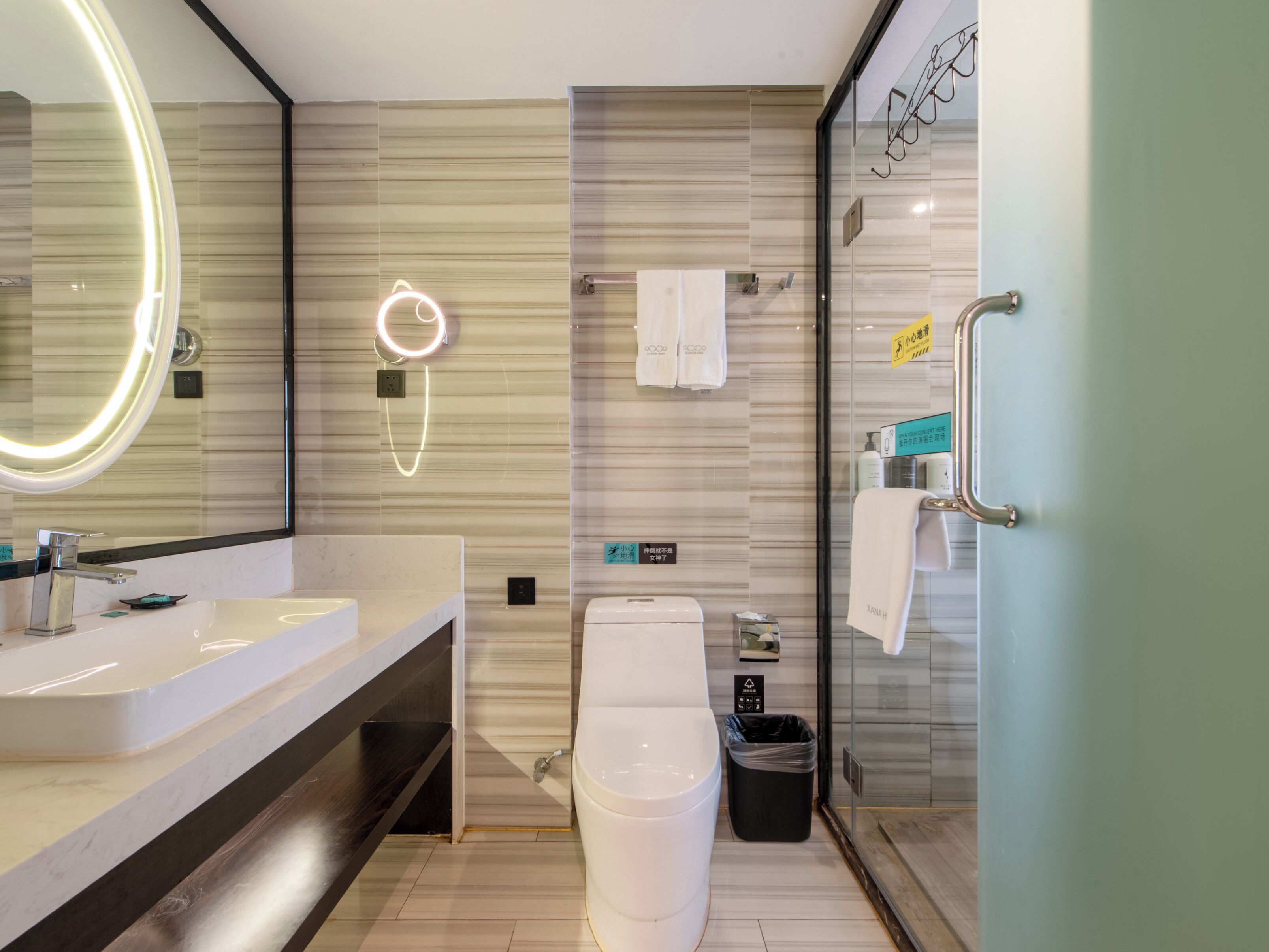 A modern bathroom with a large mirror, a toilet, a sink, and a glass shower enclosure.