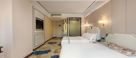 A hotel room with two beds, a large mirror, a television, and a carpet with a floral pattern.