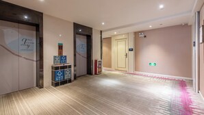A hotel corridor with carpeted flooring, a reception desk, and a door with a sign.