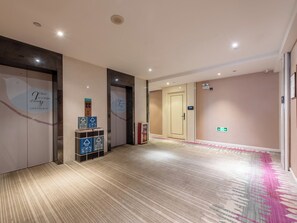 Un couloir d’hôtel avec un revêtement de sol en moquette, un comptoir de réception et une porte avec une pancarte.
