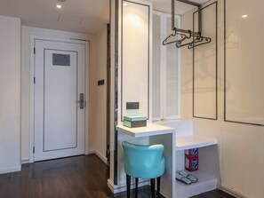 Een moderne badkamer met een witte wastafel, een spiegel, een handdoekrek en een blauwe stoel.
