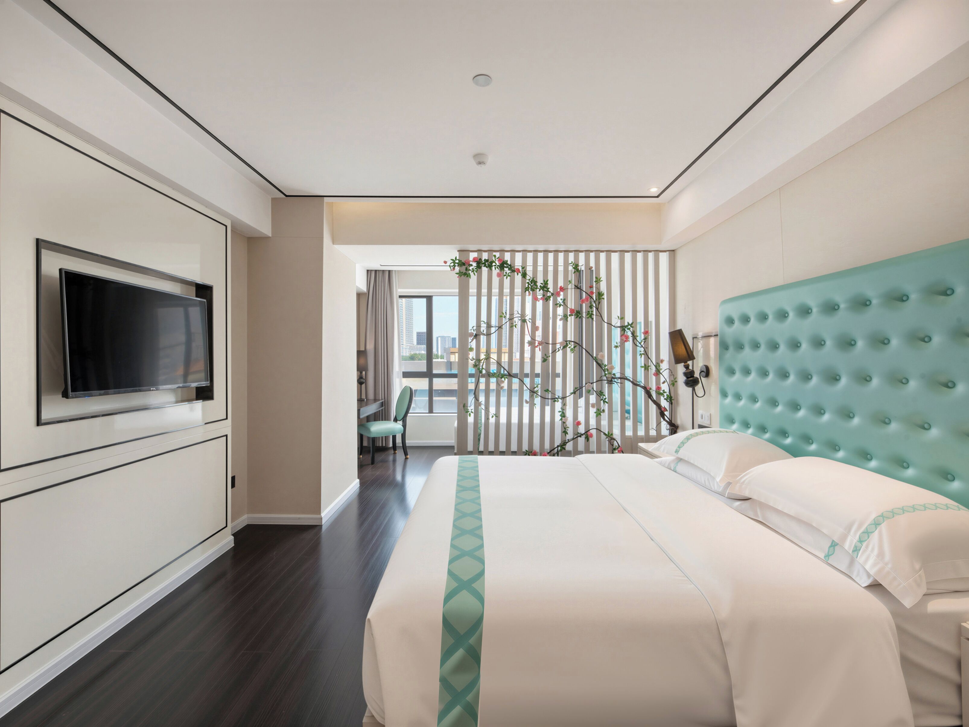 Hotelkamer met een groot bed, een aan de muur bevestigde televisie en uitzicht op de stad.
