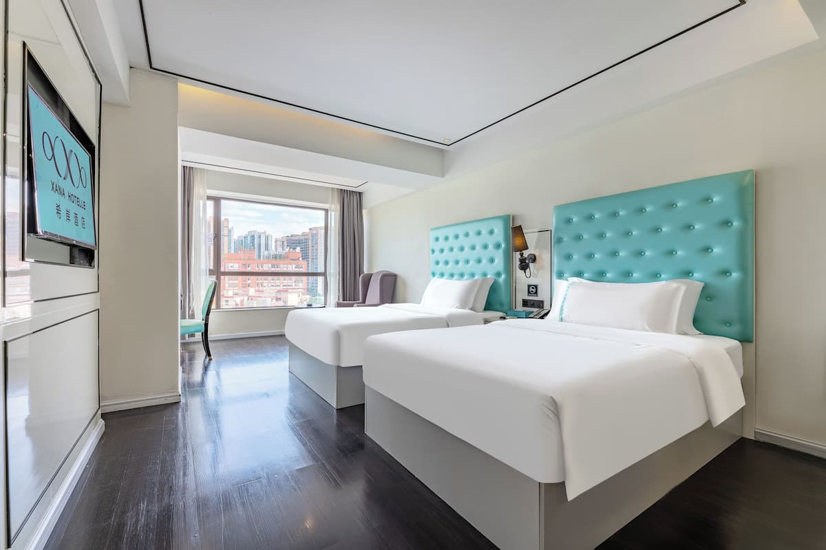 Een hotelkamer met twee bedden, een televisie en een raam met uitzicht op de stad.