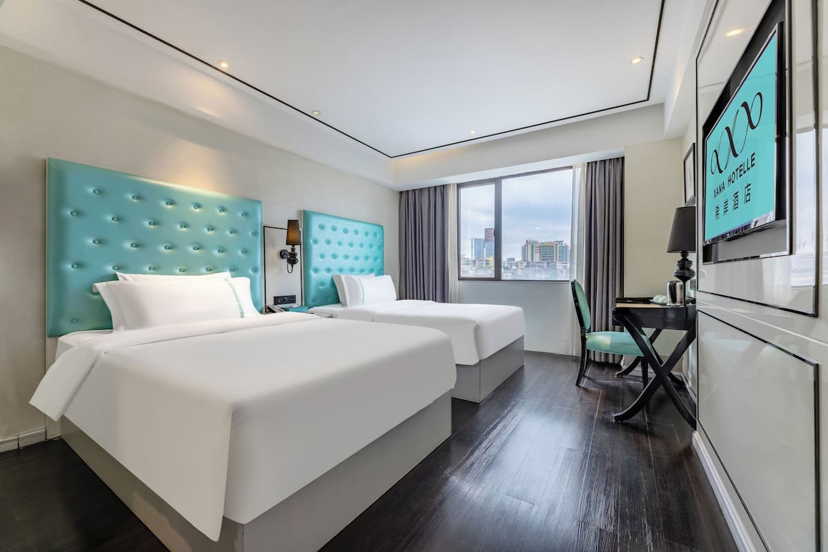 Een hotelkamer met twee bedden, een bureau, een stoel en een televisie.