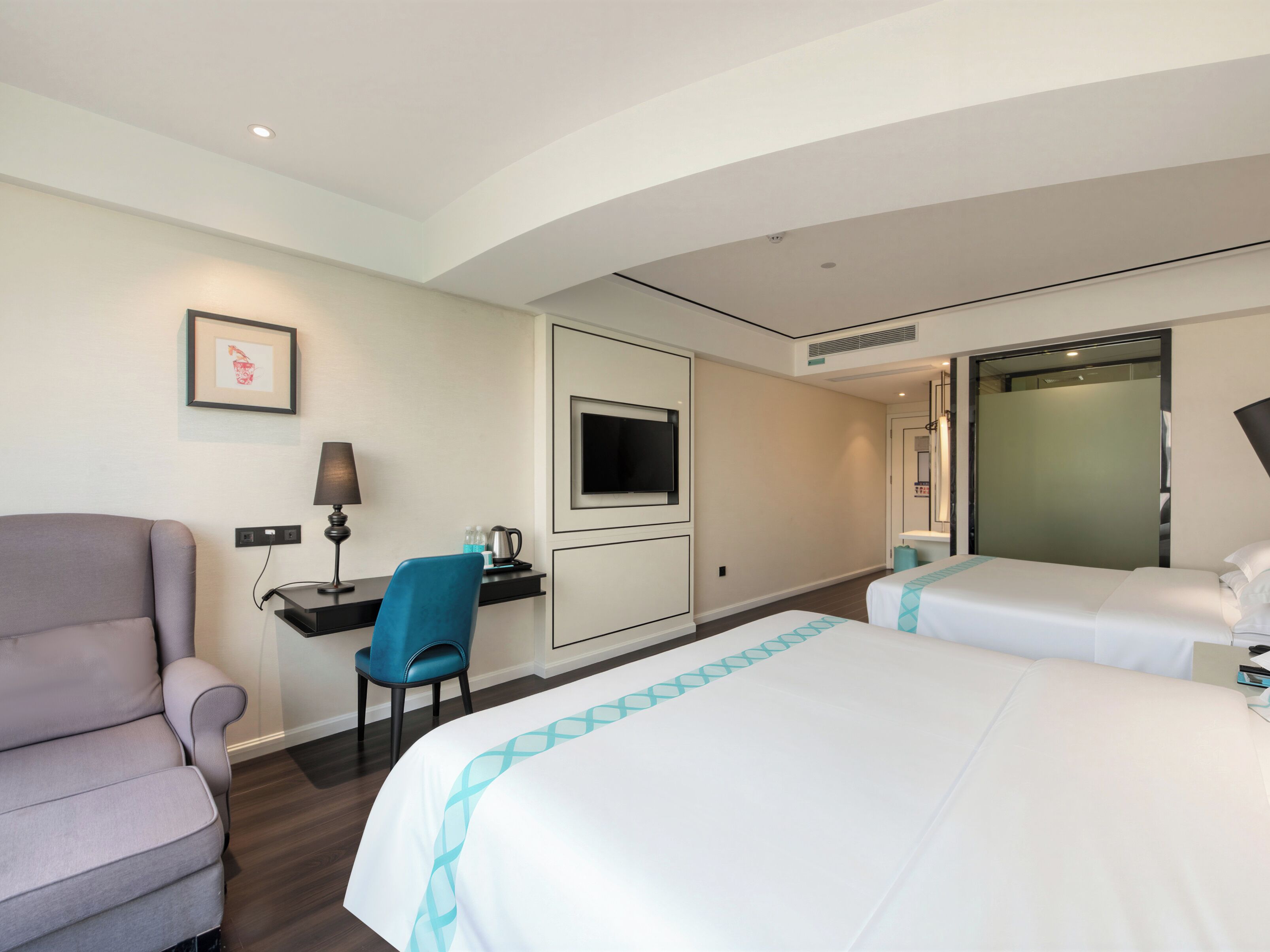 Een hotelkamer met een bed, een bureau, een stoel, een televisie en een badkamer.